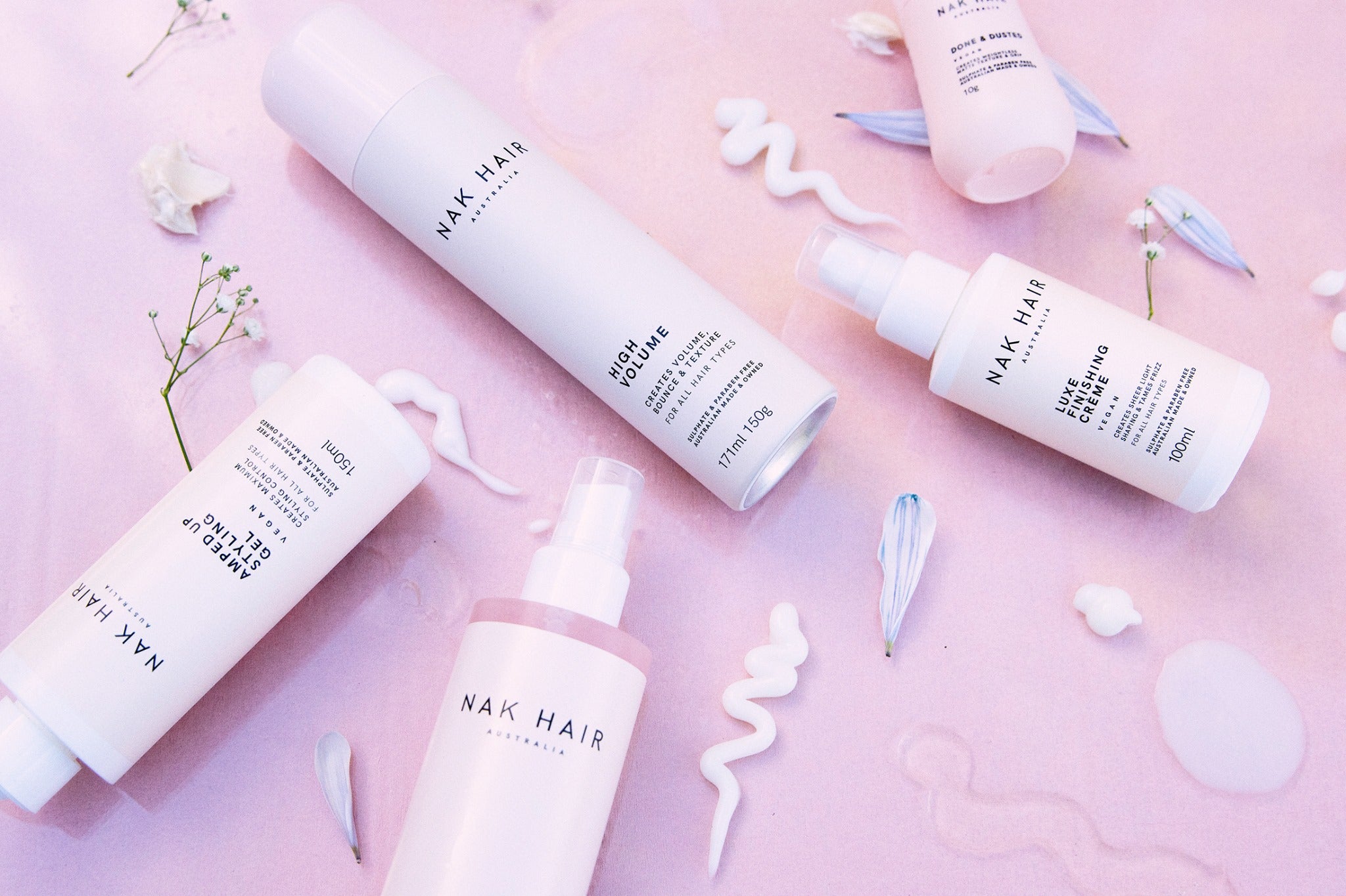 An Image of NAK Haircare Nourish Range of Shampoo, Conditioner and Treatment. Nak Nourish range with six bottles on pink background